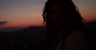 Gün batımında dağlarda bir kadının silueti.