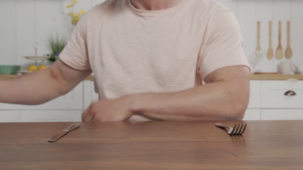 Zbliżenie ramka dziwaczny człowiek siedzi przy stole trzyma w górze talerz z myjki — Wideo stockowe