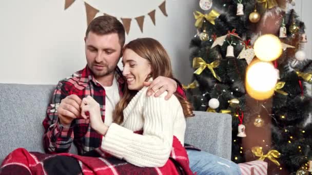 L'homme embrasse tendrement sa femme qui est assise sur ses genoux et prend sa main de façon ludique — Video