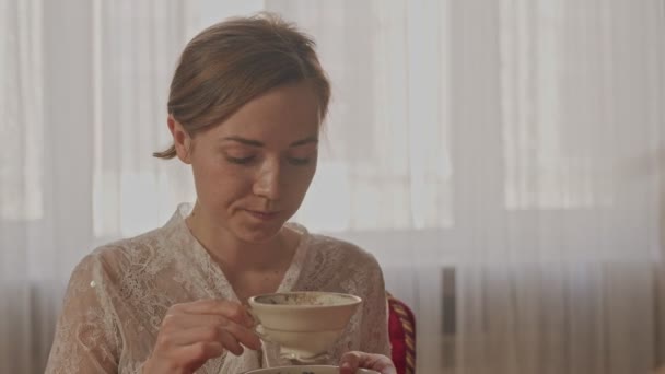 Primer plano de una hermosa chica frágil con una taza de té en sus manos — Vídeos de Stock