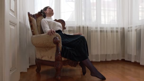 Jovem menina senta-se em uma cadeira vintage chique e se diverte e vida — Vídeo de Stock