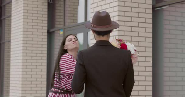 Une jeune belle fille s'est fâchée et a fouetté son petit ami avec un bouquet de fleurs — Video