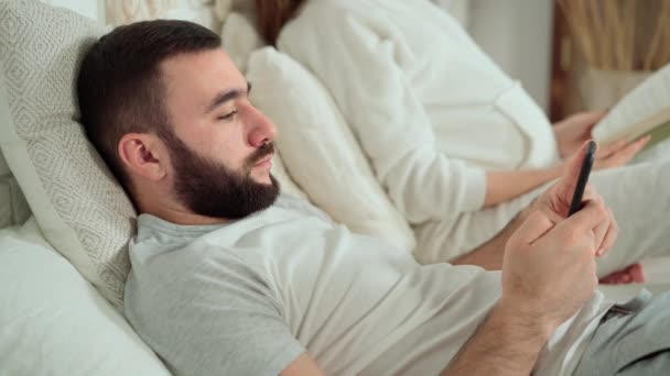 O marido descansa e trabalha ao telefone, enquanto sua esposa precisa de sua atenção — Vídeo de Stock