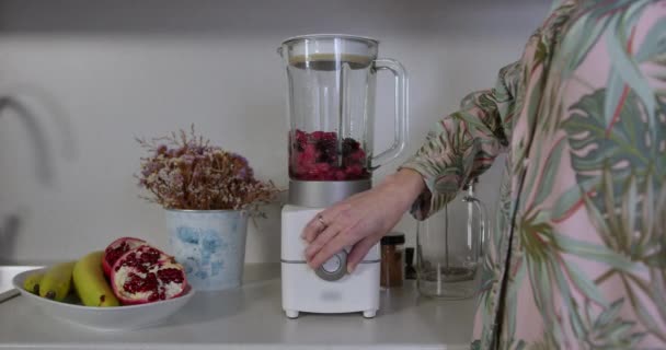 Gros plan d'une main féminine tournant doucement sur un mixeur pour préparer son smoothie frais pour le petit déjeuner — Video