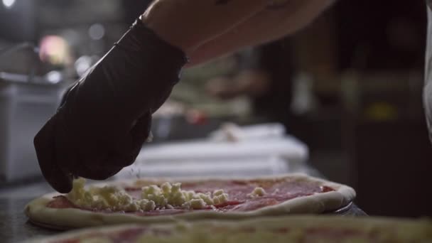Duża rama rąk producenta pizzy, który delikatnie przykrywa pizzę grubą warstwą sera — Wideo stockowe