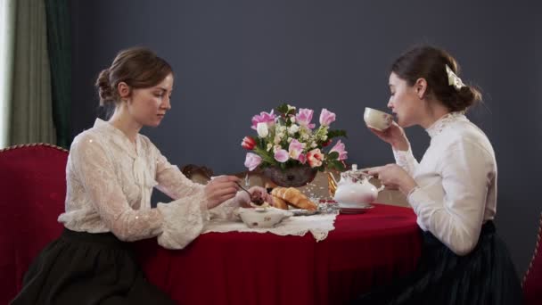 女孩子们在一张漂亮的桌子边吃饭，桌上挂着红色桌布，谈论着她们的个人恩怨 — 图库视频影像