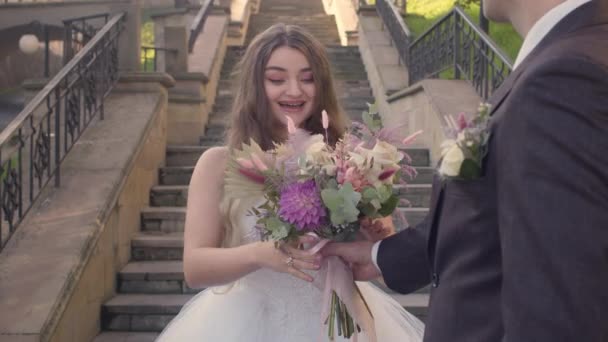 Giovane sposa felice ricevuto dal suo fidanzato uno splendido mazzo di fiori il giorno del loro matrimonio — Video Stock