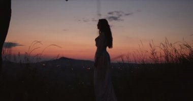 Gün batımında dağlarda ince bir siluet yalnız kız.