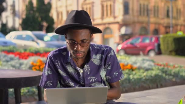 Czarny facet został w centrum w parku do pracy na laptopie — Wideo stockowe