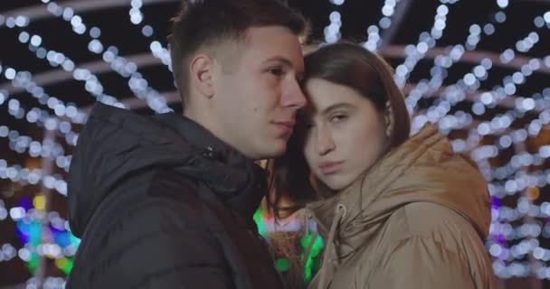Lähikuva nuoresta pariskunnasta, joka viettää aikaa yhdessä jopa kävellen ympäri uudenvuoden kaupunkia — kuvapankkivideo