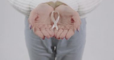 Kırılgan bir kadının elinde küçük beyaz bir kurdelenin yakın çekimi. Aile içi şiddet ile mücadelenin sembolü