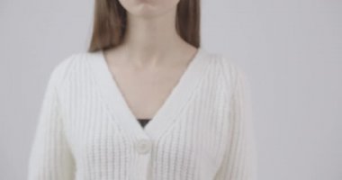 Kameranın önünde bir kızın elinde beliren küçük pembe bir kurdelenin yakın çekimi. Göğüs kanserinin sembolü.