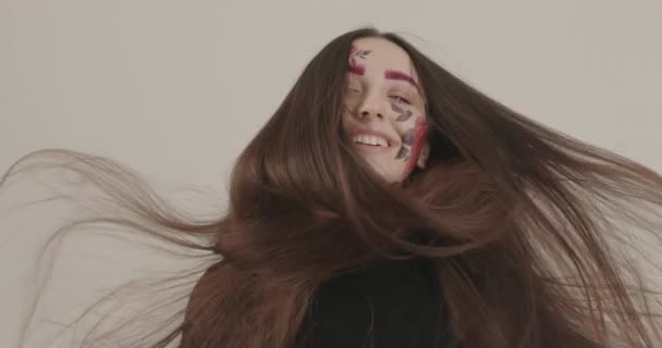 Krásná dívka s dlouhými vlasy se vyvíjí pod proudem vzduchu při fotografování ve studiu — Stock video