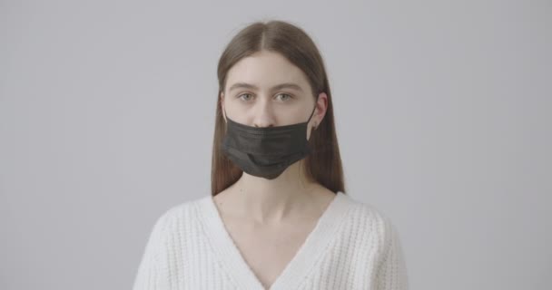 Beautiful girl with green eyes tears off her face mask symbolizing overcoming the pandemic of humanity. Stop covid-19 — Stock Video