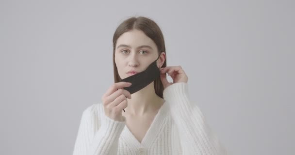 Young girl in the studio demonstrates to the camera how to properly wear and remove the protective mask — Stock Video