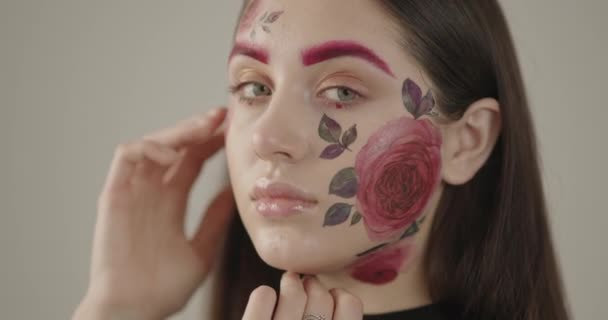 Nahaufnahme eines schönen Mädchens mit zarten Blumen im Gesicht. Symbol für Frühling und weibliche Schönheit — Stockvideo