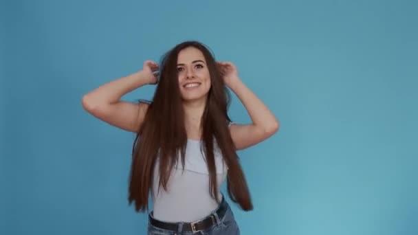 Joven chica está bailando en un estado de ánimo feliz sobre un fondo azul — Vídeos de Stock