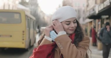 Güzel genç kız maskesini çıkarıyor ve soğuk kış havasının tadını çıkarıyor.