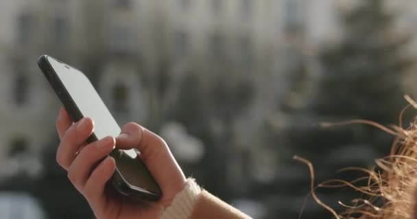 Close-up van zachte vrouwelijke handen flippen iets op de telefoon tijdens een winterwandeling — Stockvideo