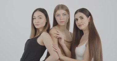 Stüdyoda gri arka planda kameraya poz veren uzun saçlı ve güzel gözlü bir manken.