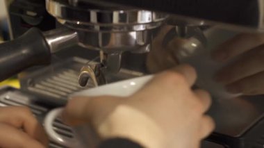 Beyaz bir fincanın çerçevesini makineden kahve dökme işlemiyle kapat