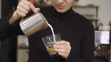 Barista profesyonel olarak kamera önünde baharatlı latte hazırlıyor.