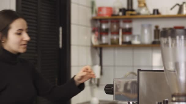Happy barista nadert zijn koffiemachine en kijkt met een zoete blik naar de camera — Stockvideo