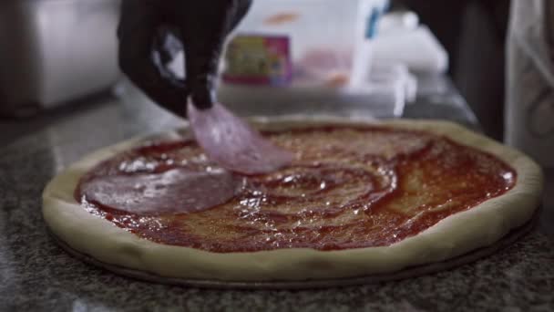 Pizzaiolo tartiner soigneusement les tranches de salami sur la sauce avant de cuire la pizza — Video