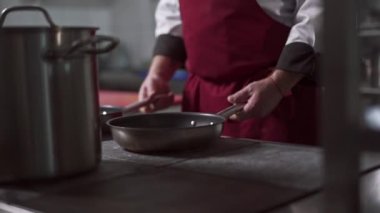 Bir restoranın mutfağında çalışmaya hazırlanan bir şefin yakın çekimi.