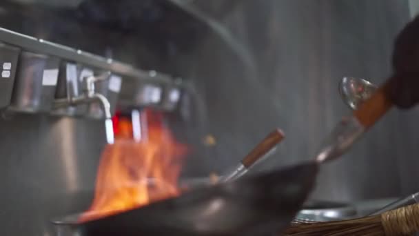 Bucătar profesionist prăjește legume într-o tigaie cu foc — Videoclip de stoc