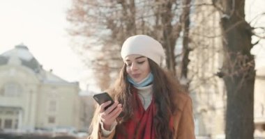 Uzun siyah saçlı kız soğuk havada yüzünde koruyucu bir maskeyle şehirde dolaşmaktan hoşlanıyor.