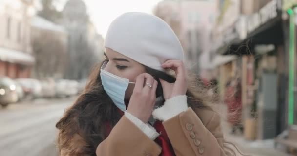 Красивая девушка надевает маску и призывает людей заботиться о себе и бороться с пандемией — стоковое видео