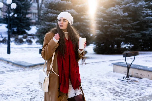 Genç kız işe giderken yolda kendini ısıtan güzel kokulu kahve içerek sokakta yürüyor.