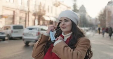 Genç ve güzel bir kız koruyucu maskesini çıkarır ve temiz soğuk havayı göğsüne üfler.