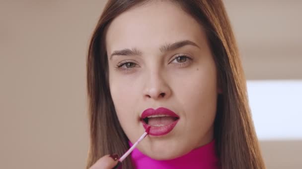 Das Mädchen bemalt ihre Lippen mit rosa Lippenstift und blickt selbstbewusst in die Kamera. Der Influencer macht sein Make-up. — Stockvideo