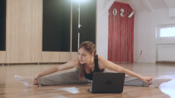 这个女孩在做伸展运动.她和一位教练一起参加网上课程. — 图库视频影像