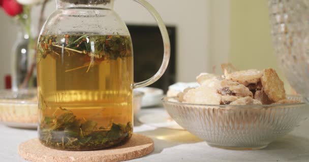 Te i en transparent tekanna på bordet med kakor på en tallrik. Örtte. — Stockvideo