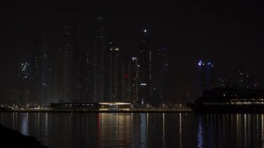 Gece şehri. Yüksek binalar gece deniz kenarında parlar..