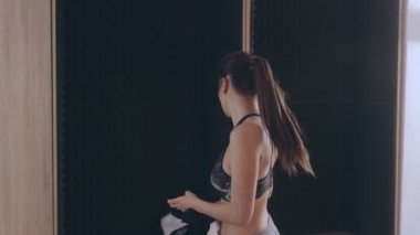 Kız eğitimden sonra giysilerini değiştiriyor. Siyah tişörtünü çıkardı ve parlak pembe bir golf kıyafeti giydi.