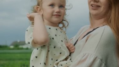 Mom holds the baby in her arms. The child is greeted with hand gestures.