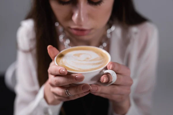 Dziewczyna trzymająca filiżankę cappuccino. Wzór na kawie. Dziewczyny trzymają filiżankę kawy.. — Zdjęcie stockowe