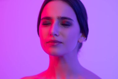 Göz yaşlarıyla şımartılmış makyaj. Genç bir kızın yanağında gözyaşları. Ağlayan ve acı çeken kız neon ışıkta.