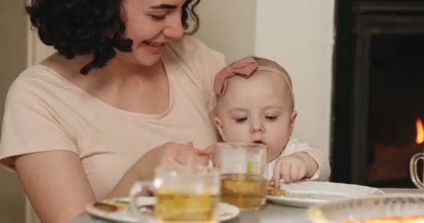 La mère tient le bébé dans ses bras et boit du thé en ce moment. Maman permet à l'enfant d'explorer le monde. — Video