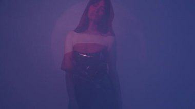 Plastik bir elbiseyle neon ışıkta dans eden bir dansçı. Kız polietilen giymişti..