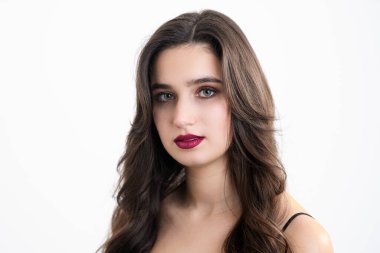 Makyajlı ve stil sahibi kız kameraya bakıyor. Beyaz arka planda bir kızın fotoğrafı..