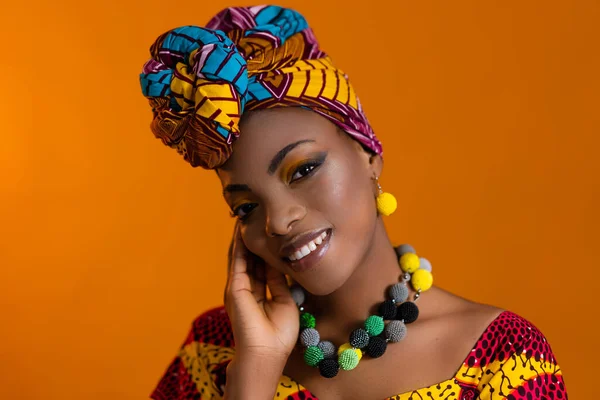 Afrikalı bir kadının vücudunda boncukları olan parlak mücevherler. Kafasında parlak bir türban.