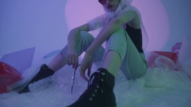 Mode flicka sitter på golvet runt hennes polyeten innehåll. Skräp som vi själva valde. — Stockvideo