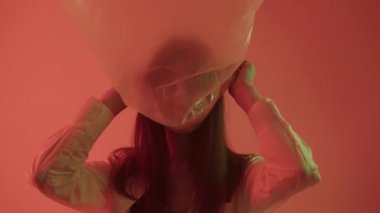 Kız kafasına naylon poşet geçirmiş ve bu da plastik poşetlerle basitliğini gösteriyor..