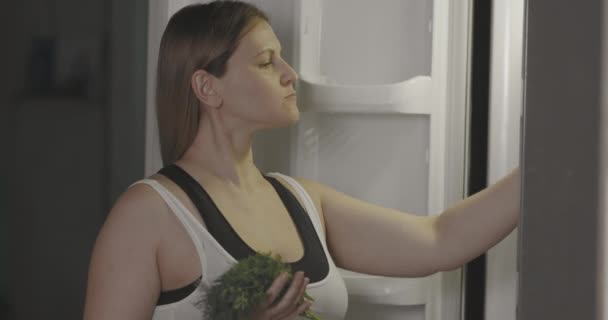 La mujer embarazada por la noche come alimentos saludables del refrigerador. Comer verduras con placer. — Vídeos de Stock