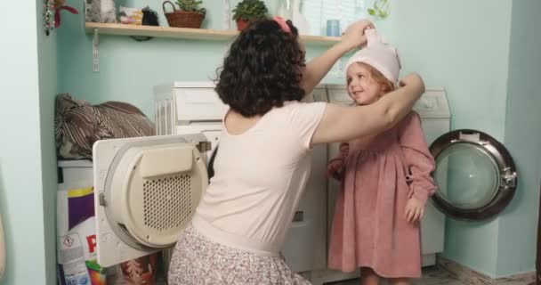 Maman et fille jouent dans la salle de bain. La mère a mis des collants sur la tête de ses filles, improvisant un lapin. Bonne enfance. — Video